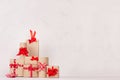 Festive home decor with many kraft gift boxes with red ribbons on white wood board, copy space.