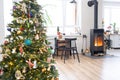 Festive interior of house is decorated for Christmas and New Year in loft style with black stove, fireplace, Christmas tree. Warm Royalty Free Stock Photo