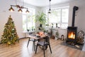 Festive interior of house is decorated for Christmas and New Year in loft style with black stove, fireplace, Christmas tree. Warm Royalty Free Stock Photo