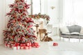 Festive living room interior with decorated Christmas tree, fireplace and decorative deers. Royalty Free Stock Photo
