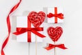 Festive love background - white gift boxes with red silk ribbons, sweet lollipops hearts on white wood board, closeup. Royalty Free Stock Photo