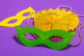 Festive Mardi Gras masquerade purple background. Fat Tuesday carnival, masks, beads, traditional decor Royalty Free Stock Photo