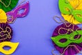 Festive Mardi Gras masquerade violet background. Fat Tuesday carnival, masks, beads, traditional decor Royalty Free Stock Photo