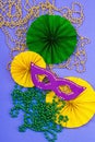 Festive Mardi Gras masquerade violet background. Fat Tuesday carnival, masks, beads, traditional decor Royalty Free Stock Photo