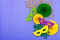 Festive Mardi Gras masquerade violet background. Fat Tuesday carnival, masks, beads, traditional decor Royalty Free Stock Photo