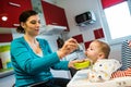 Festive meal. Mother feeding baby solid food for the first time Royalty Free Stock Photo