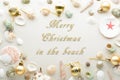 Festive Merry Christmas greeting text surroundedby a frame of baubles and seashells for a summer or tropical theme