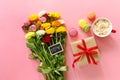 Festive morning concept buttercup flowers bouquet, gift box, cup of cappuccino and makarons cake on the pink background.