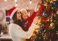 Festive mother and daughter decorating Christmas tree at home Royalty Free Stock Photo