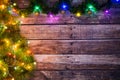 Festive New Year or Christmas background of dark old wooden boards, Christmas tree and luminous garland with colored lights and Ch Royalty Free Stock Photo