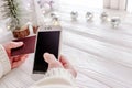 Festive online shopping at its coziest: A pair of hands in a snug sweater clutching a smartphone and a bank card