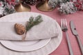 Festive place setting with beautiful dishware, cutlery and cone for Christmas dinner on pink tablecloth, closeup Royalty Free Stock Photo