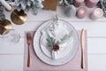 Festive place setting with beautiful dishware, cutlery and cone for Christmas dinner on white wooden table, flat lay Royalty Free Stock Photo