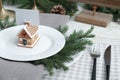 Festive place setting with beautiful dishware, cutlery and gingerbread house card holder for Christmas dinner on white wooden Royalty Free Stock Photo