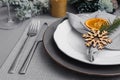Festive place setting with beautiful dishware, fabric napkin and dried orange slice for Christmas dinner on grey table, closeup Royalty Free Stock Photo