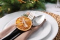 Festive place setting with beautiful dishware, fabric napkin and dried orange slice for Christmas dinner on white table, closeup Royalty Free Stock Photo