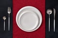 Festive place setting with red napkin. Empty plates and silver cutlery on dark black background. Top view. Dining table in Royalty Free Stock Photo