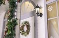 Festive porch entrance door way with lantern and decorative wreath on white facade Christmas holidays Royalty Free Stock Photo