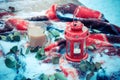 Festive red candle in lantern and mug of coffee on rug with snow Royalty Free Stock Photo