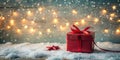 A festive red gift box adorned with a satin bow rests on a snowy surface, illuminated by warm string lights and falling snowflakes Royalty Free Stock Photo