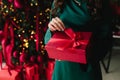 Festive red gift held against a sparkling Christmas tree background. Royalty Free Stock Photo