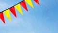 Festive ribbon of red and yellow triangle flags on the white clouds and blue sky background Royalty Free Stock Photo