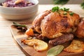 Festive roast chicken fresh from the oven with apples, kumquat, spices and herbs served with red cabbage on a wooden table,