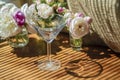 Festive rustic still life with glass empty clear glass surrounded by white flowers on textile background on wooden table. Diagonal