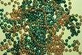 Shiny Green and Gold Beads On Light Green Background - Festive Backdrop for St. Patrick`s Day or Mardi Gras