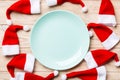 Festive set of plate decorated with Santa Claus hat on wooden background. Top view christmas dinner concept Royalty Free Stock Photo