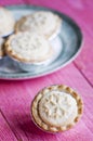 Festive shortcrust pastry mince pies. A sweet mince pie, a traditional rich festive food on pink wooden background. Royalty Free Stock Photo