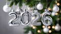 Festive silver 2026 Christmas ornaments hanging from a green tree branch Royalty Free Stock Photo