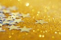 Festive silver stars on a sparkling golden background. Free space for an inscription. Pre-holiday mood Royalty Free Stock Photo