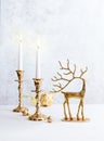 Festive still life with burning candles, figure of deer and Christmas decorations on pastel light background. Christmas