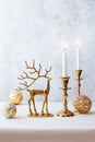 Festive still life with burning candles, figure of deer and Christmas decorations on pastel light background. Christmas