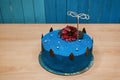 Festive sweet delicious cake with blue cream decorative birthday gift stands on a wooden table