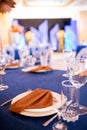 Festive table with blue cloth, napkins, plates, cutlery and glasses prepared for wedding guests in restaurant. Beautiful Royalty Free Stock Photo