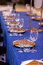 Festive table with blue cloth, napkins, plates, cutlery and glasses prepared for wedding guests in restaurant. Beautiful Royalty Free Stock Photo