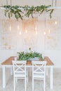 Festive table decorated with garland of branches eucalyptus on the center and candles. Decor christmas table retro garlands. The