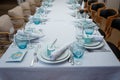 Festive table set with white cloth, plates, forks blue glasses and bomboniere for boy happy birthday party.