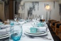 Festive table set with white cloth, plates, forks blue glasses and bomboniere for boy happy birthday party.