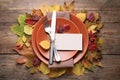 Festive table setting with autumn leaves and blank card on wooden background, flat lay Royalty Free Stock Photo
