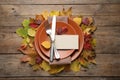 Festive table setting with autumn leaves and blank card on wooden background, flat lay Royalty Free Stock Photo