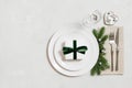 Festive table setting for Christmas dinner on gray table. A gift in a plate, silver decorations on a gray background. View from Royalty Free Stock Photo