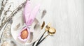 Festive table setting for Easter. A napkin in the form of an Easter bunny on a plate with cutlery. Light background. Copy space