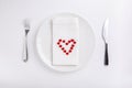 Festive table setting. Empty plate, knife, fork, napkin and red  heart on white table. Top view, flat lay, copy space Royalty Free Stock Photo