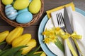 Festive table setting with flowers and painted eggs on wooden background. Easter celebration Royalty Free Stock Photo