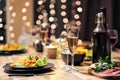 Festive table setting. Food and drinks, plates and glasses. Evening lights and candles. New Year`s Eve. Royalty Free Stock Photo