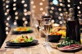 Festive table setting. Food and drinks, plates and glasses. Evening lights and candles. New Year`s Eve. Royalty Free Stock Photo