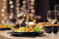 Festive table setting. Food and drinks, plates and glasses. Evening lights and candles. New Year`s Eve. Royalty Free Stock Photo